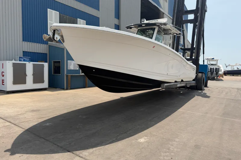 Slide: The Image of 2021 Caymas 341 CC boat on forklift at marina, blue building background. - 4