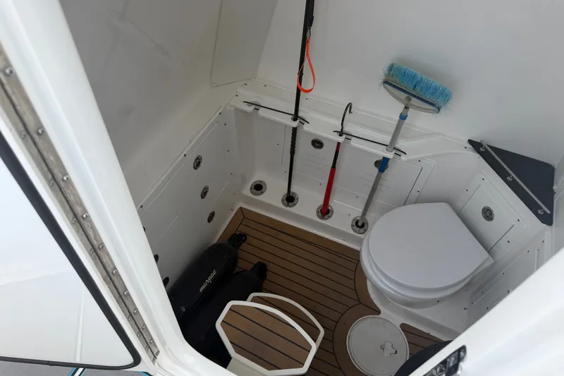 Slide: The Image of Interior of 2021 Caymas 341 CC boat featuring a compact bathroom with storage and cleaning tools. - 42