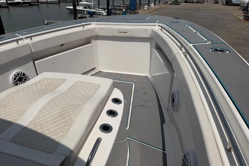Slide: The Image of 2021 Caymas 341 CC boat interior with cushioned seating and speakers at a marina. - 17