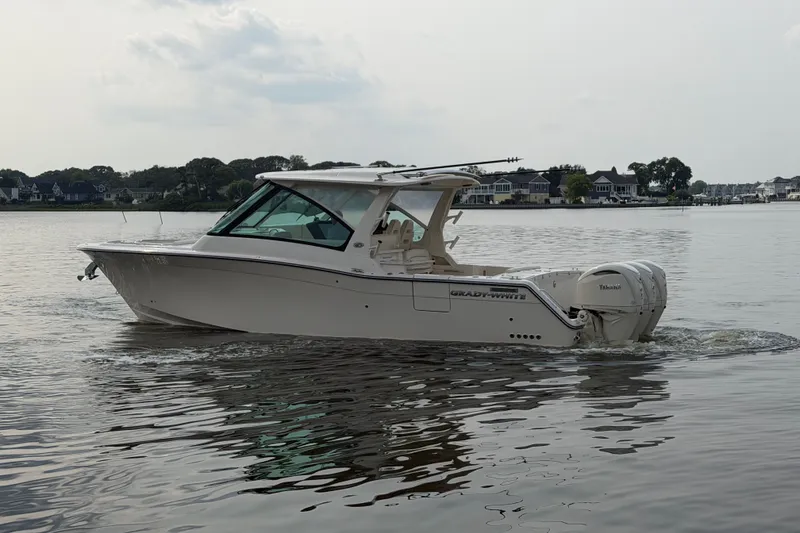 Slide: The Image of 2027 Grady-White Freedom 345 boat cruising on calm waters near residential shoreline. - 3