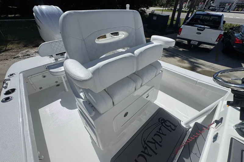 Slide: The Image of 2025 BlackJack 256 Coastal boat interior with white seating and steering wheel. - 32