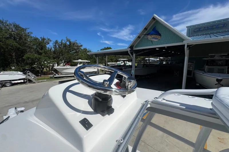 Slide: The Image of 2025 BlackJack 256 Coastal boat steering wheel at a marina under a clear blue sky. - 27