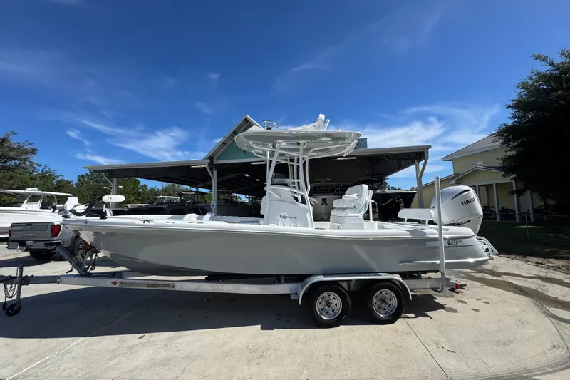 The Image of 2025 BlackJack 256 Coastal boat on trailer under clear blue sky. - 1