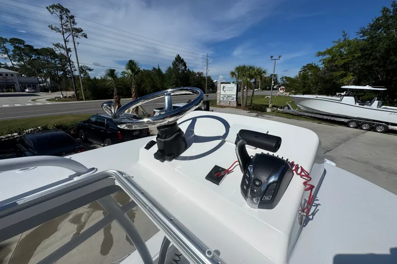 Slide: The Image of 2025 BlackJack 256 Coastal boat helm with steering wheel and controls, parked outdoors. - 26