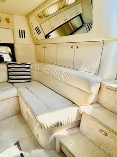 Slide: The Image of Interior of a 1999 Sea Ray 410 Express Cruiser with beige sofa and striped pillow. - 5