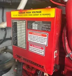 Slide: The Image of A red Westerbeke generator casing with warning labels and a high voltage sign. - 25