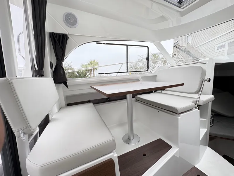 Slide: The Image of 2024 Beneteau Antares 8 interior with white seating and wooden table. - 8