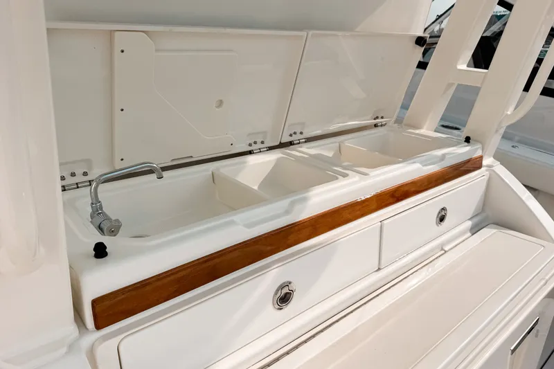 Slide: The Image of 2027 Pursuit S 328 Sport boat sink and storage area with wooden trim. - 9