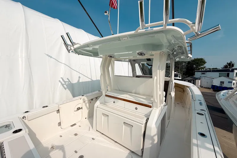 Slide: The Image of 2027 Pursuit S 328 Sport boat interior with seating and storage, docked outdoors. - 7