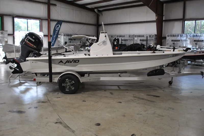 The Image of 2023 Avid 19 FS boat on trailer in showroom with Yamaha engine. - 1
