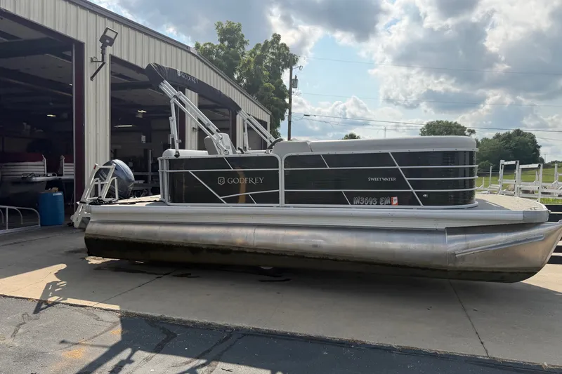 Slide: The Image of 2023 Godfrey Sweetwater 2086 CX pontoon boat parked outside a warehouse. - 2