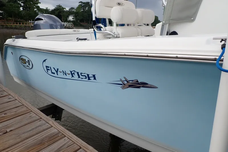 Slide: The Image of 2017 Sea Hunt Ultra 211 boat with "Fly-N-Fish" graphic docked by water. - 8