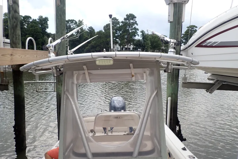 Slide: The Image of 2017 Sea Hunt Ultra 211 boat docked, featuring fishing rod holders and a clear canopy. - 31