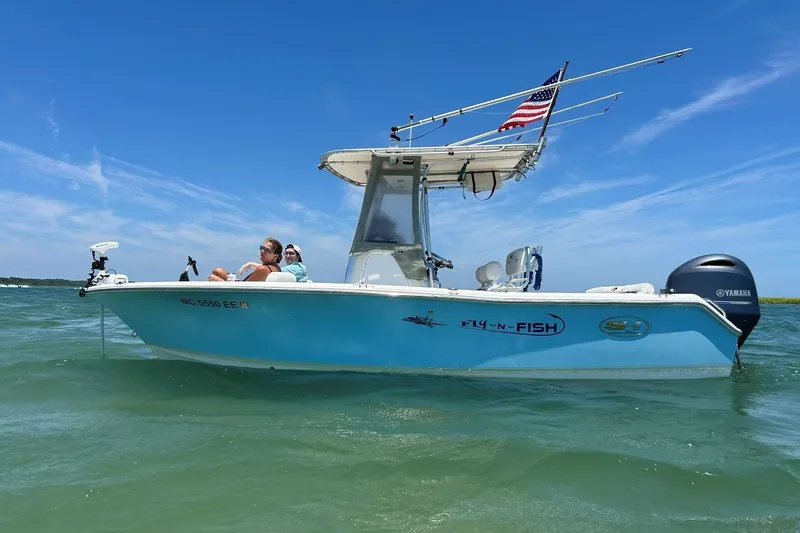 The Image of 2017 Sea Hunt Ultra 211 boat on water, with passengers, American flag, and Yamaha motor. - 0