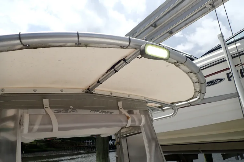 Slide: The Image of 2017 Sea Hunt Ultra 211 boat canopy with mounted light, docked near another vessel. - 29