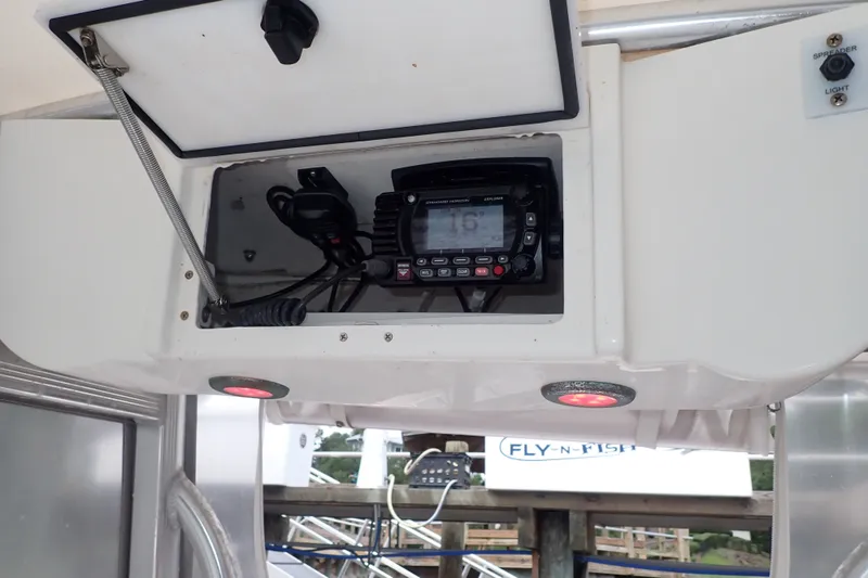 Slide: The Image of 2017 Sea Hunt Ultra 211 boat radio compartment with VHF radio and spreader light switch. - 24
