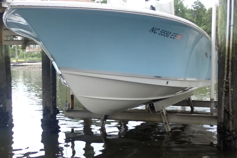 Slide: The Image of 2017 Sea Hunt Ultra 211 boat on lift, blue hull, docked in calm water. - 5