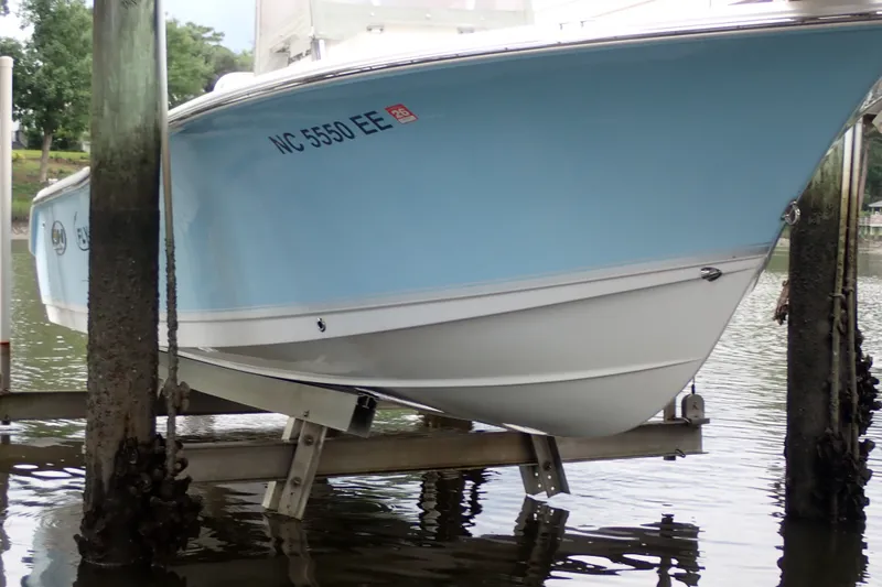 Slide: The Image of 2017 Sea Hunt Ultra 211 boat on lift, light blue hull, docked by water. - 4
