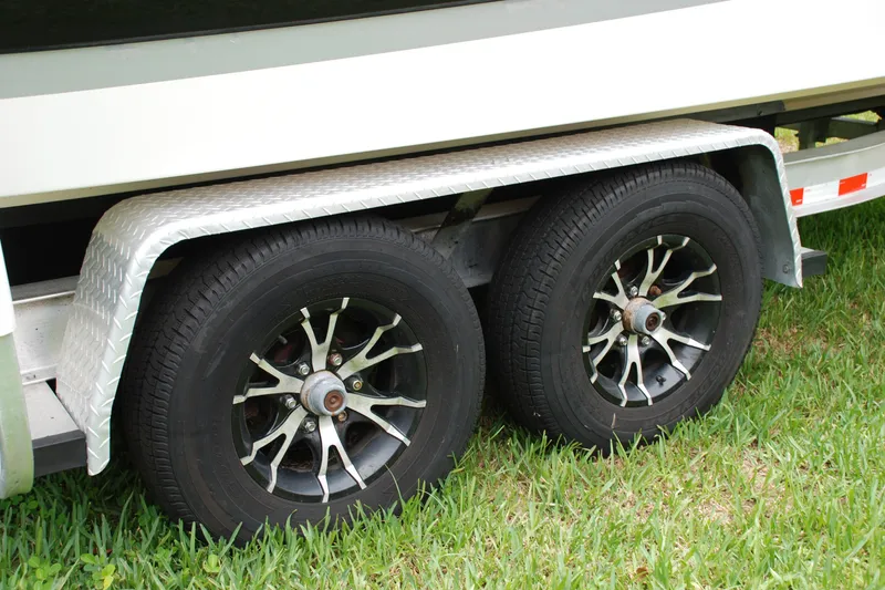 Slide: The Image of Trailer wheels of a 2014 Scarab 255 boat on grass. - 21