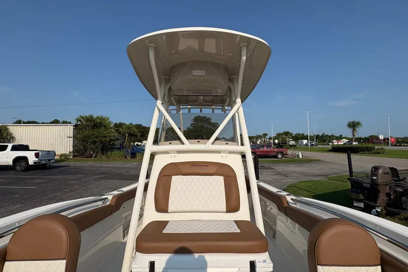 Slide: The Image of 2027 Pioneer 222 Islander boat with tan and white seating, parked outdoors. - 25