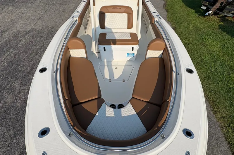 Slide: The Image of 2027 Pioneer 222 Islander boat interior with brown and white seating, docked on grass. - 30