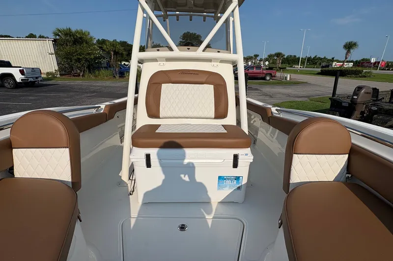 Slide: The Image of 2027 Pioneer 222 Islander boat interior with brown and white seating, cooler, and shadow. - 24