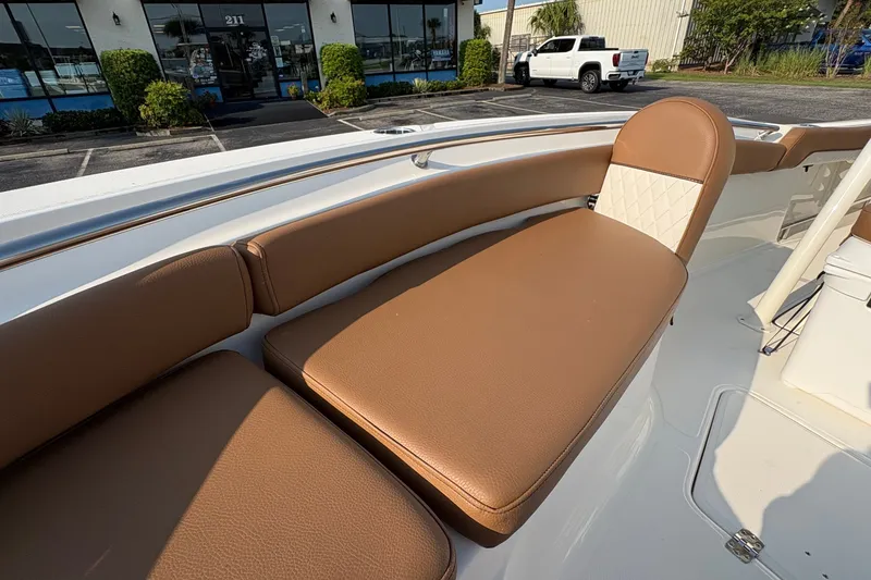 Slide: The Image of 2027 Pioneer 222 Islander boat with brown cushioned seating in a parking lot setting. - 26