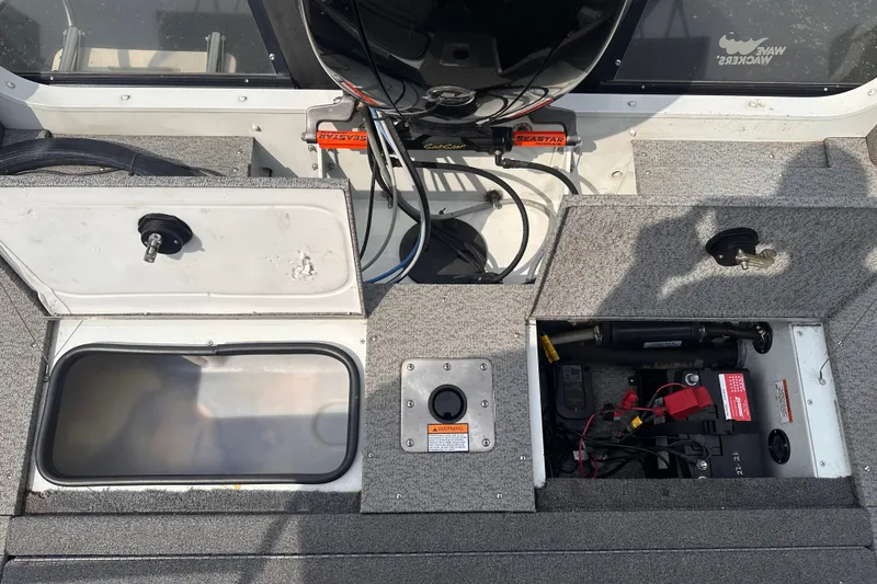 Slide: The Image of 2013 Alumacraft Competitor 185 Sport boat interior with open storage compartments and visible wiring. - 25