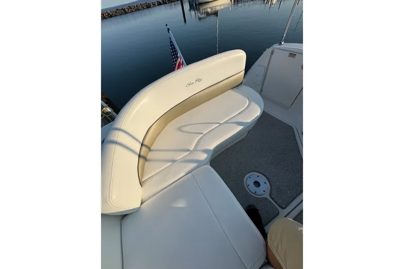 Slide: The Image of 2006 Searay 260 boat interior with cushioned seating and American flag in marina setting. - 13