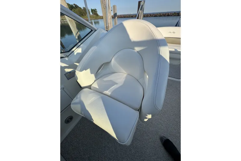 Slide: The Image of White leather seat on 2006 Sea Ray 270 Sundancer boat, docked by calm waters. - 17