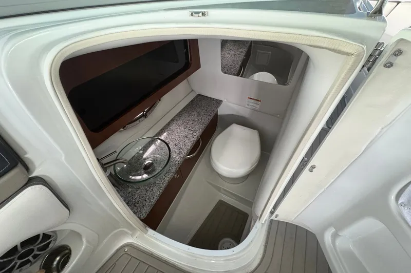 Slide: The Image of 2021 Crownline 290 SS boat interior with modern bathroom, featuring a toilet and glass sink. - 22