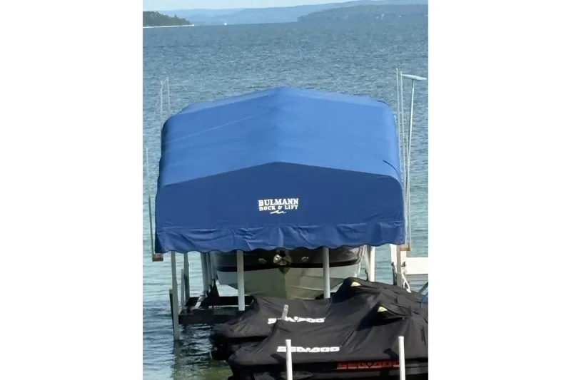 Slide: The Image of Covered Crownline 290 SS boat on a dock with blue canopy by the water. - 26