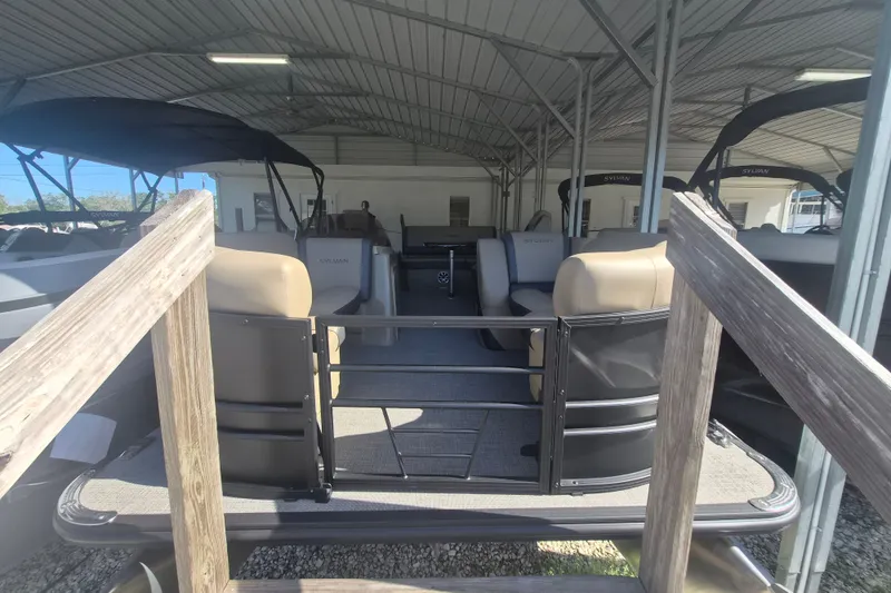 The Image of 2026 Sylvan X3 DLZ DH BAR pontoon boat under a metal canopy. - 1