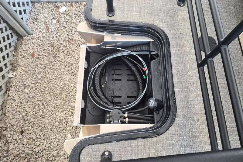 Slide: The Image of Storage compartment of 2026 Sylvan X3 DLZ DH BAR boat with coiled hose and fittings. - 20