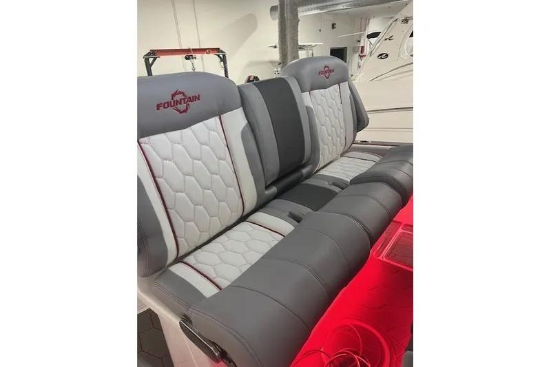 Slide: The Image of 2025 Fountain 34 SC boat seats with gray and white upholstery, red accent lighting. - 21