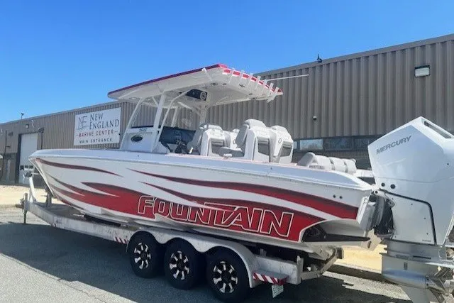 Slide: The Image of 2025 Fountain 34 SC boat with red and white design on a trailer outside a marine center. - 1