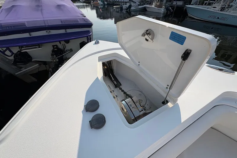 Slide: The Image of 2022 Sea Hunt Ultra 275SE boat anchor compartment open at marina. - 11