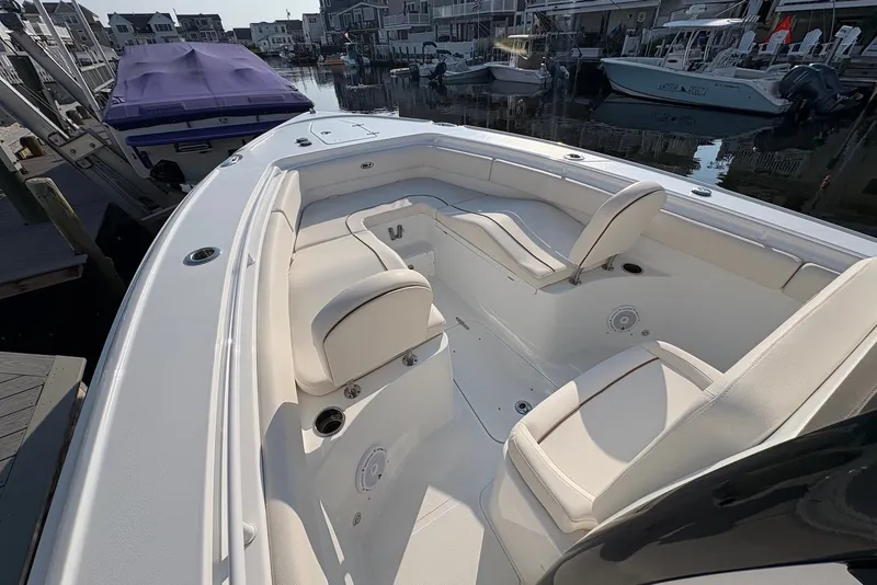 Slide: The Image of 2022 Sea Hunt Ultra 275SE boat interior with white seating in a marina. - 9