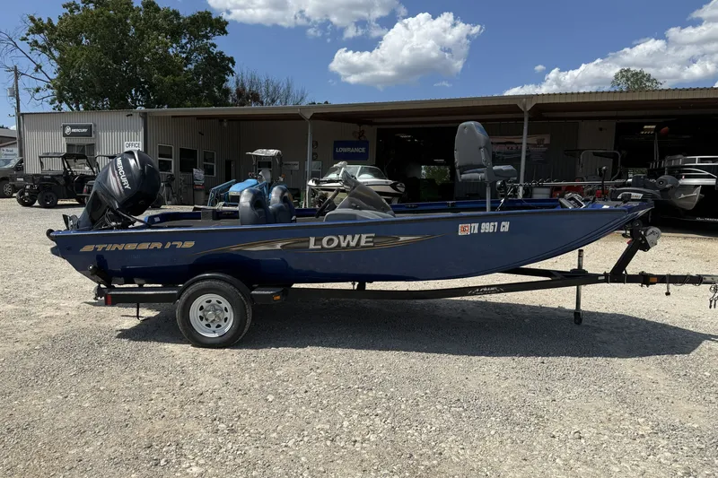 Slide: The Image of 2014 Lowe Stinger 175 boat on trailer, parked outdoors under a clear sky. - 3