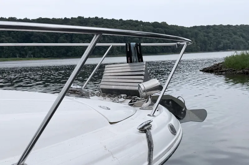 Slide: The Image of 2006 Sea Ray Sundancer 320 boat anchored on a serene lake with lush green shoreline. - 4