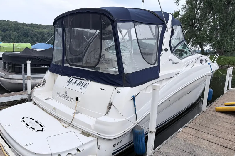 Slide: The Image of 2006 Sea Ray Sundancer 320 docked, featuring a blue canopy and sleek white design. - 1
