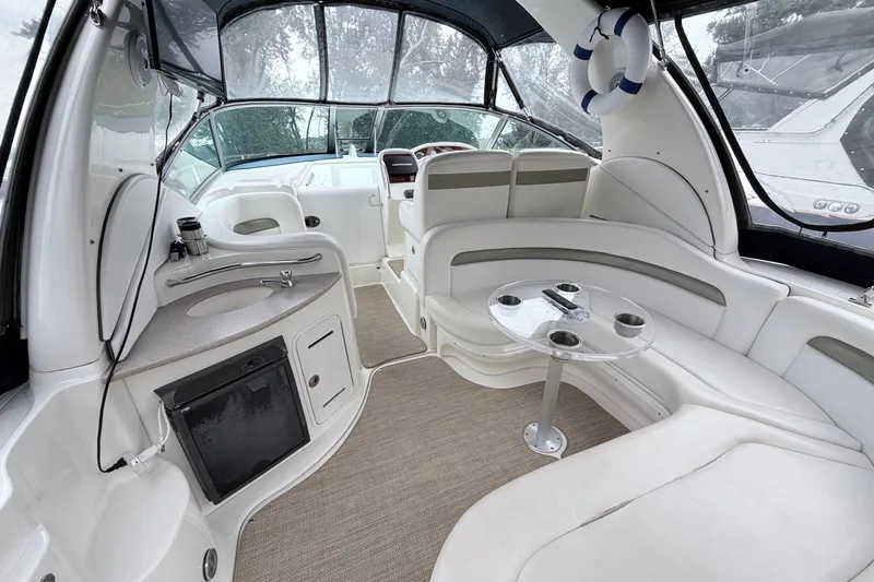 Slide: The Image of 2006 Sea Ray Sundancer 320 interior with white seating, compact kitchenette, and circular table. - 5
