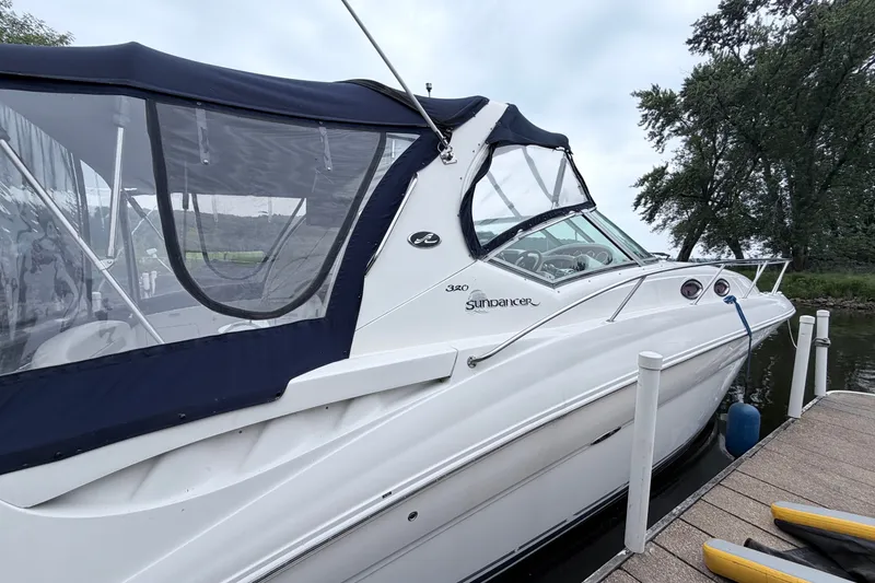 Slide: The Image of 2006 Sea Ray Sundancer 320 docked, featuring sleek design and blue canopy. - 2