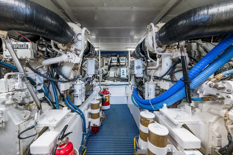 Slide: The Image of Engine room of 1998 Buddy Davis 58 Sportfisherman, featuring Caterpillar engines and blue hoses. - 29