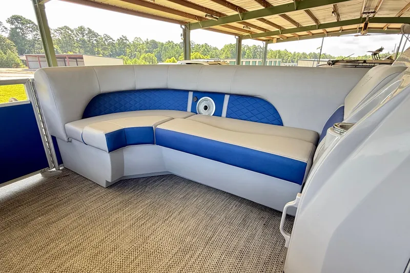 Slide: The Image of 2024 Bennington L22 boat interior with blue and gray seating under a covered area. - 21