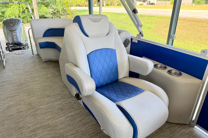 Slide: The Image of 2024 Bennington L22 boat interior with blue and white seating, cup holders, and motor view. - 16