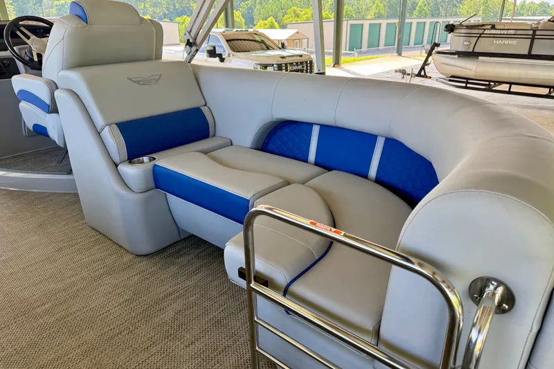 Slide: The Image of 2024 Bennington L22 boat interior with blue and gray seating, cup holder, and railing. - 11