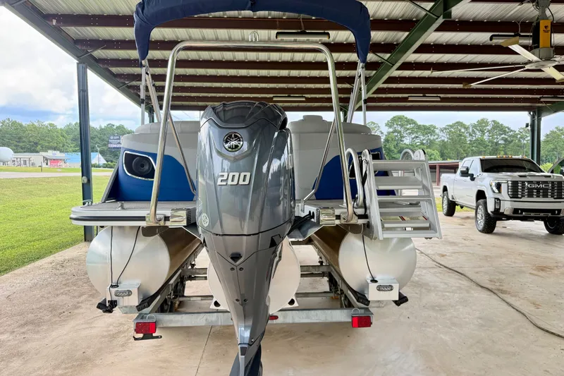 Slide: The Image of 2024 Bennington L22 pontoon boat with Yamaha 200 engine, parked under a metal canopy. - 3