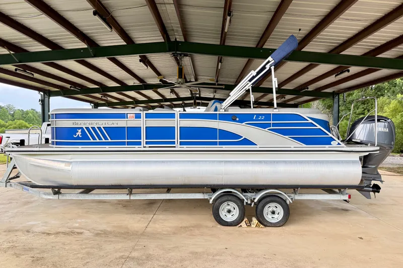 Slide: The Image of 2024 Bennington L22 pontoon boat on trailer under metal roof. - 1