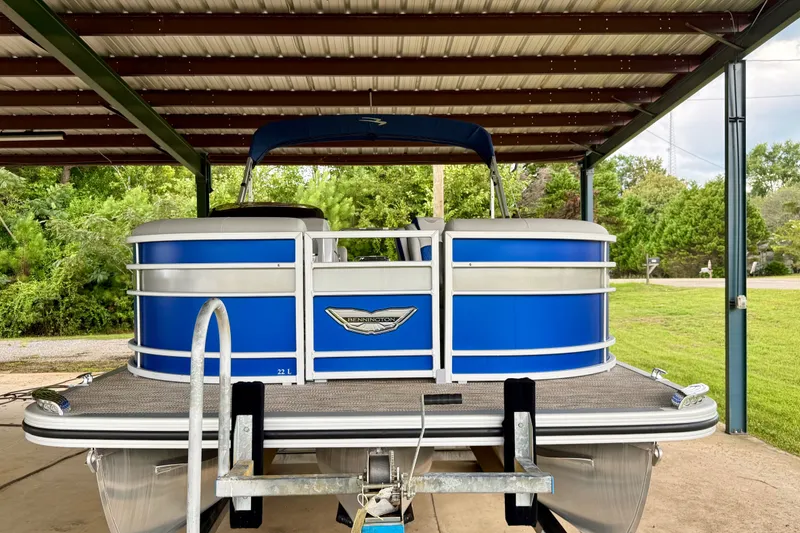 Slide: The Image of 2024 Bennington L22 pontoon boat under a metal canopy, showcasing sleek blue design. - 7